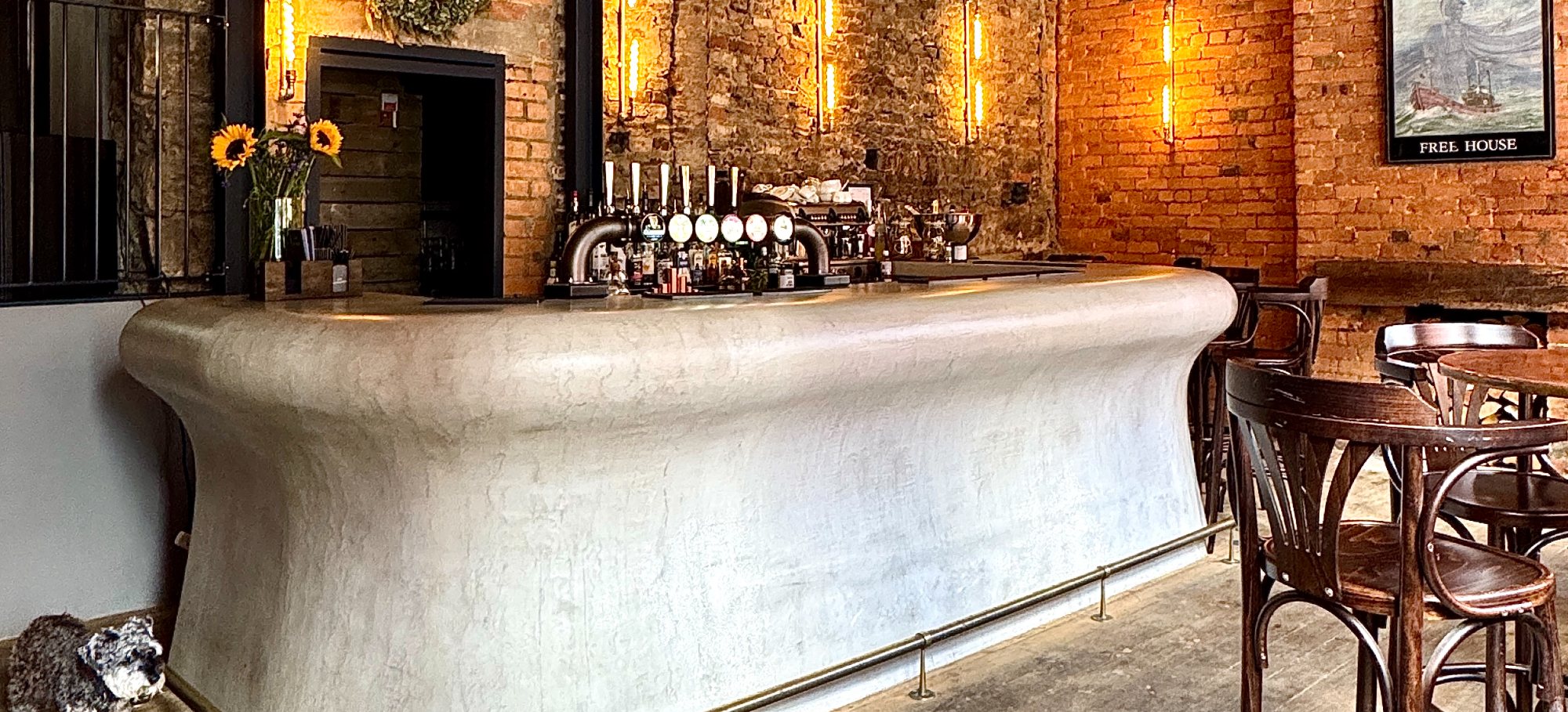The curved plaster bar at The Britannia, exposed brick and filament light